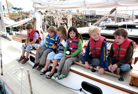 summer camp kids sit on sailboat