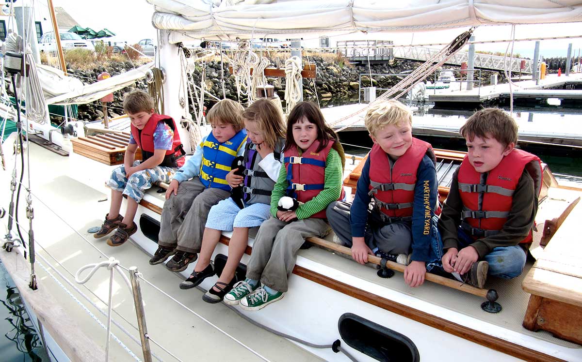 summer camp kids sit on sailboat